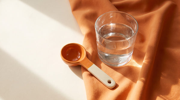 Cucchiaino di ceramica e bicchiere d'acqua alla luce del sole