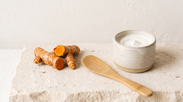Radice essiccata e vasetto di crema a confronto su un piano di pietra chiara