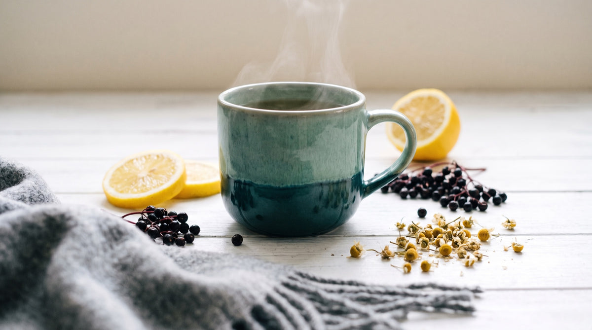 Tisana fumante, limone e fiori secchi su legno chiaro