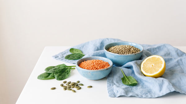 Lenticchie, spinaci e limone su un piano di ceramica chiara