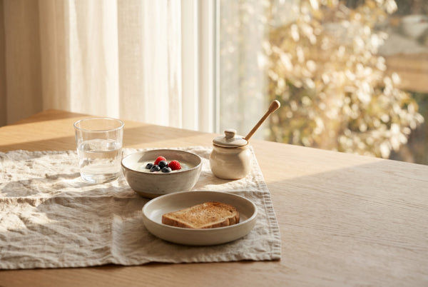 Colazione soleggiata: bicchiere d'acqua, yogurt e luce del mattino, il momento per la vitamina D