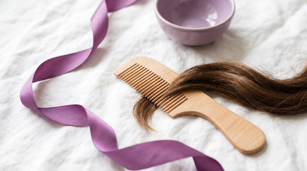 Pettine di legno e ciocca di capelli lucidi su lino chiaro
