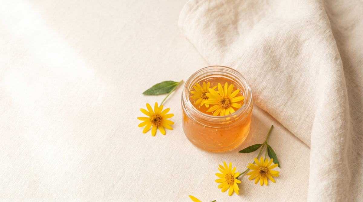 Vasetto di gel aperto con fiori di arnica su asciugamano chiaro