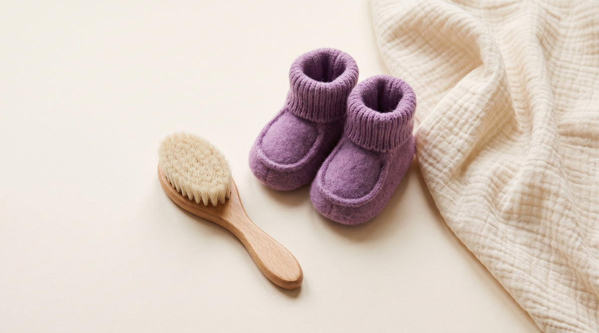 Spazzola in legno con scarpine da neonato lilla e copertina
