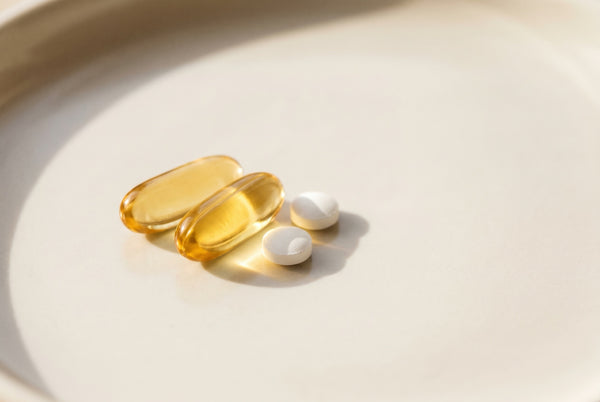 Capsule di vitamina D e compresse su un piattino chiaro: la dose quotidiana
